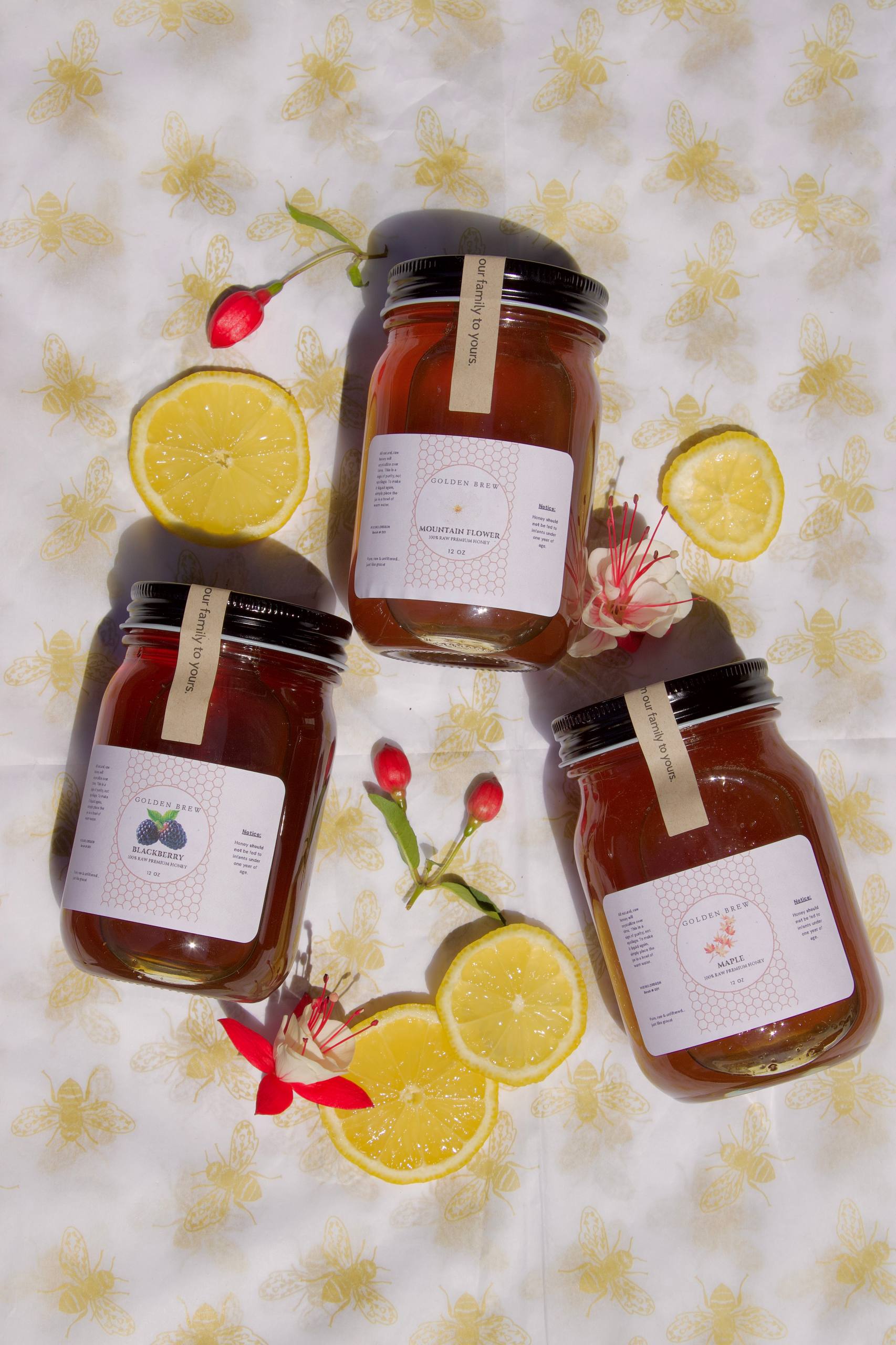 The Golden Trio — three jars of Golden Brew Oregon honey on bee-pattern fabric with lemons, lavender, and red flowers