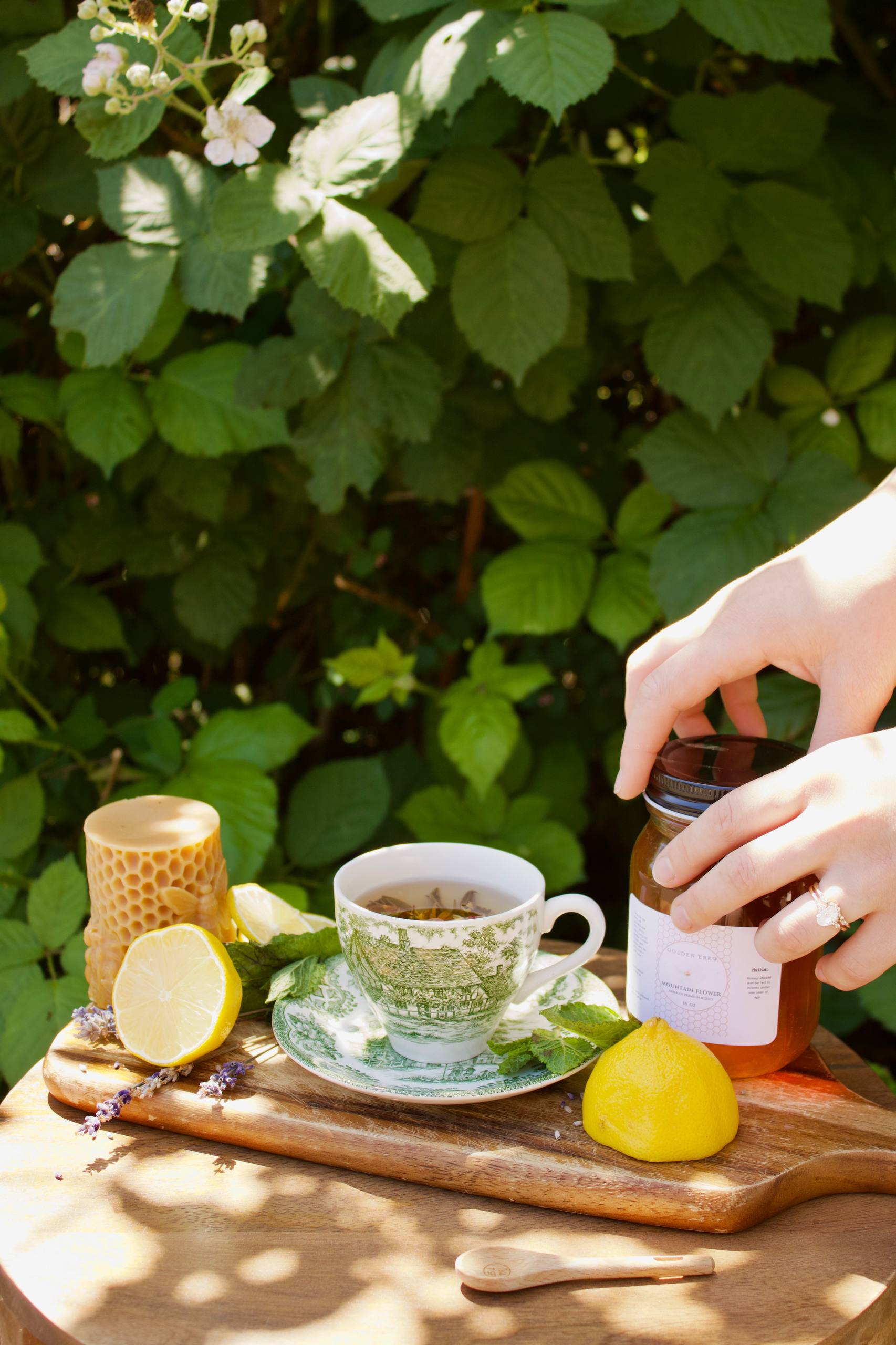 Vintage tea cup, lemon, and a jar of Golden Brew Oregon Mountain Flower Honey on a wooden board